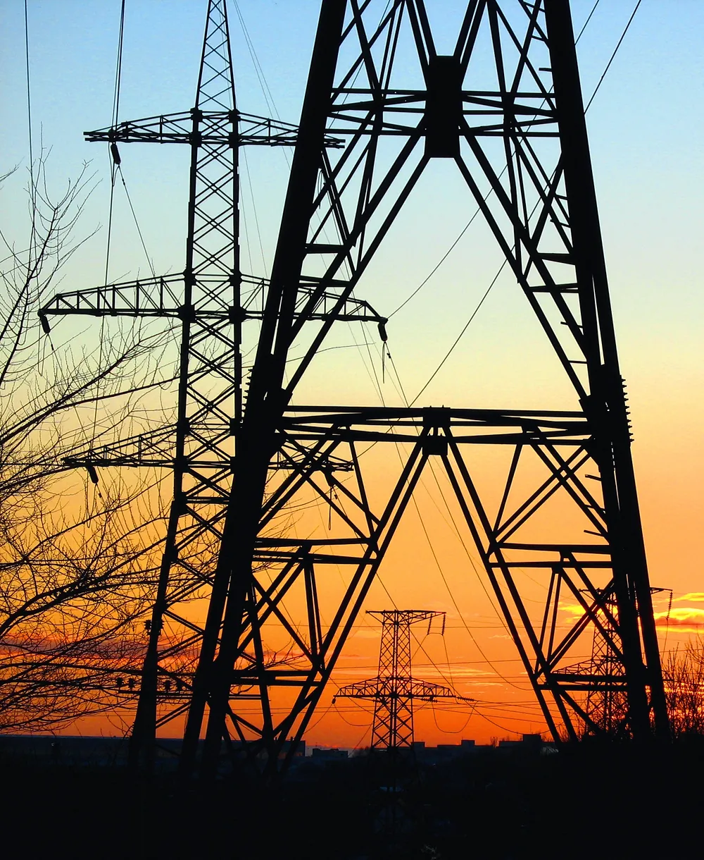 High-voltage transmission tower silhouetted against a sunset sky
